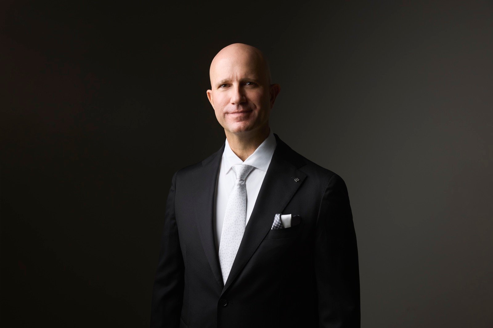 Marvin J. Schmidt, formal portrait in a black suit and silver tie.