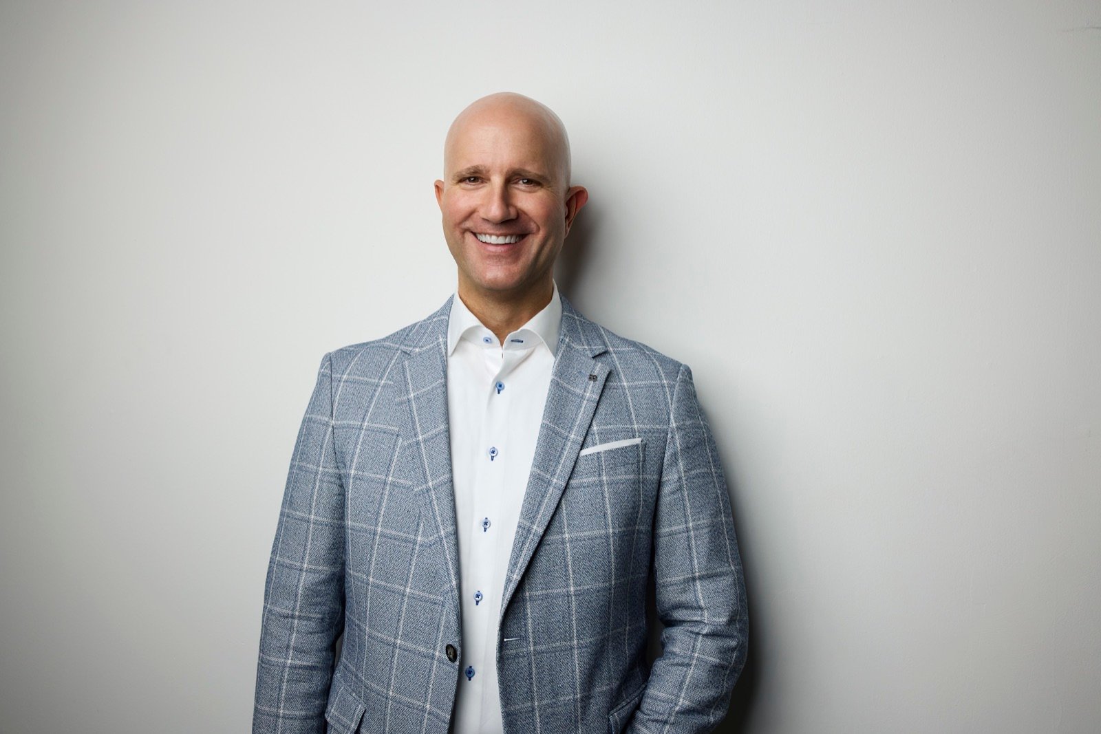 Marvin J. Schmidt smiling in a gray windowpane blazer against a white background.